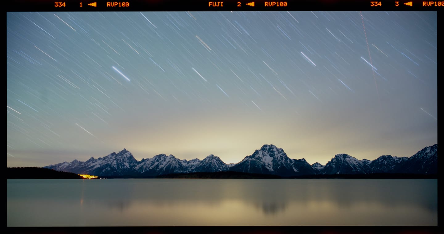 Star trails over snowy mountains and a still lake on Fujifilm Velvia 100, 6×12 panoramic.