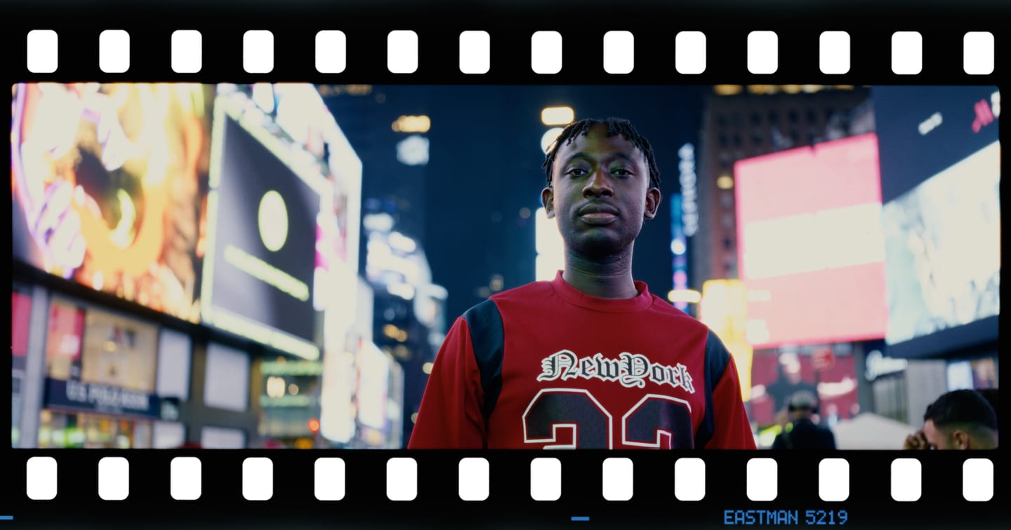 A man in a red jersey in Times Square on Kodak Vision3 500T, XPan panoramic, printed on Kodak Vision 2383.